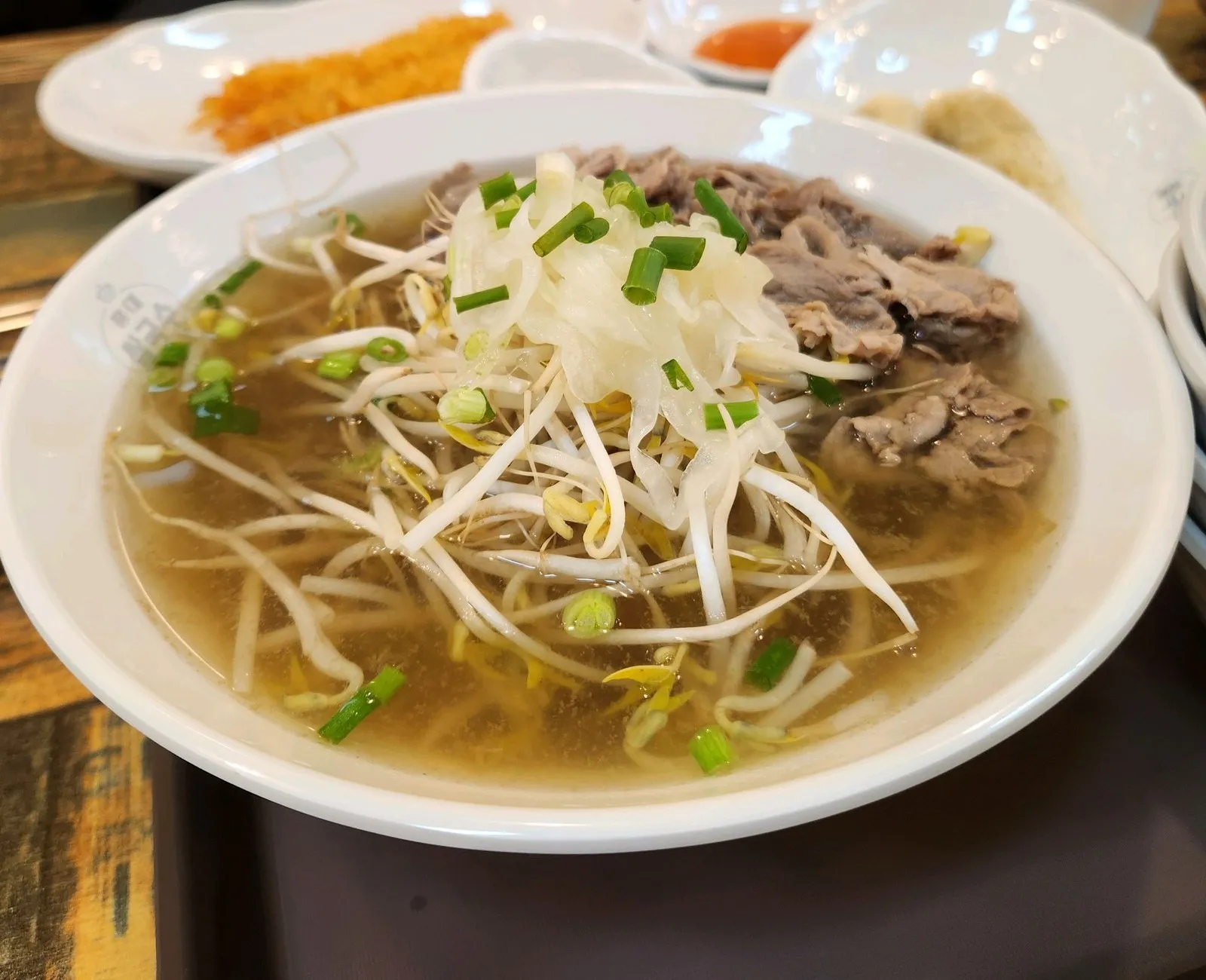 쌀국수 한 그릇 — 맑은 국물 위에 숙주와 양파, 고기를 올려 내줍니다