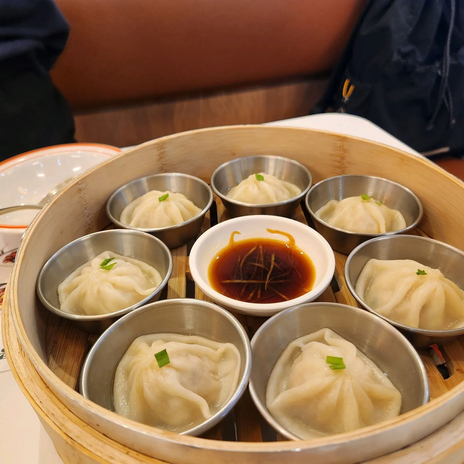 샤오롱바오 — 대나무 찜기에 한 알씩 스테인리스 종지에 담겨 나오고, 가운데는 생강채를 올린 소스