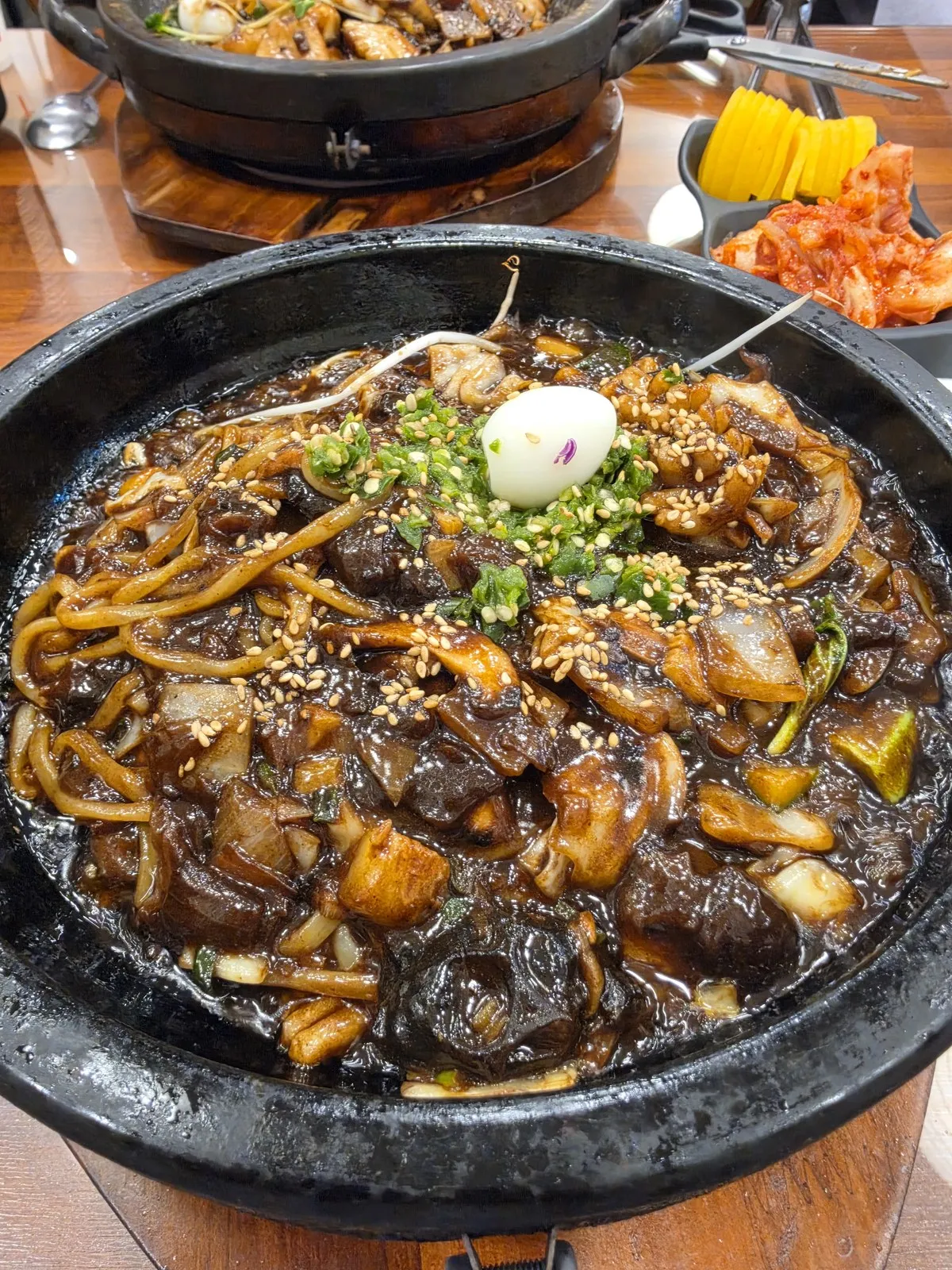 큼직한 돌판에 담겨 나온 짜장 — 가운데 메추리알과 부추, 참깨가 올라갑니다
