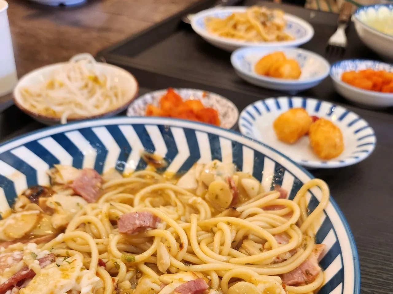 Little side-dish bowls next to the pasta — you can see kimchi and seasoned bean sprouts