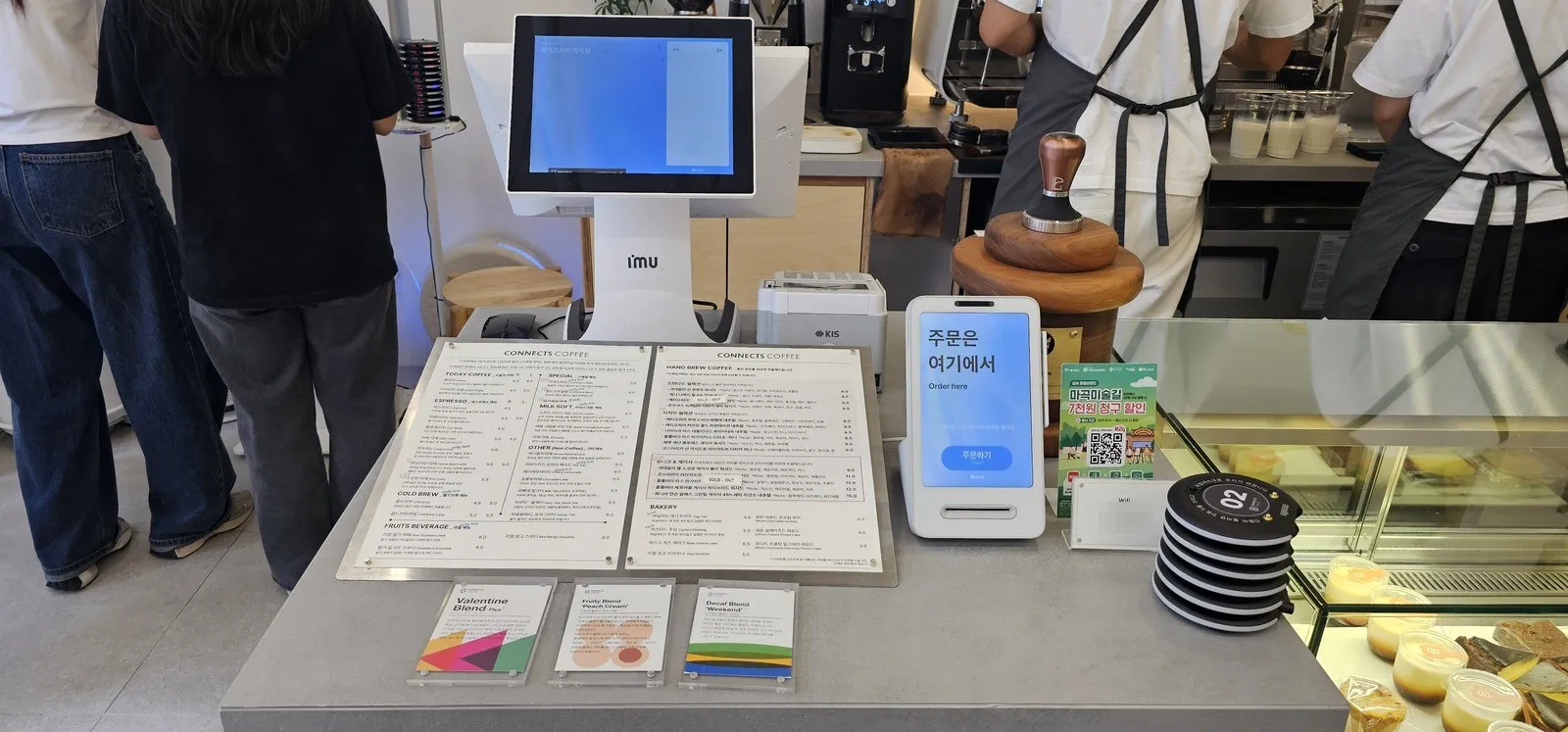 카운터 — 메뉴판 두 장, 원두 카드 세 장, 주문 단말과 진동벨