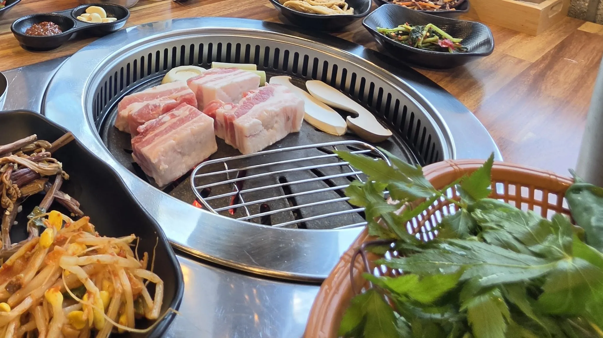 생삼겹살 — 두툼하게 썰어 나옵니다. 새송이와 마늘, 파가 같이 올라갑니다