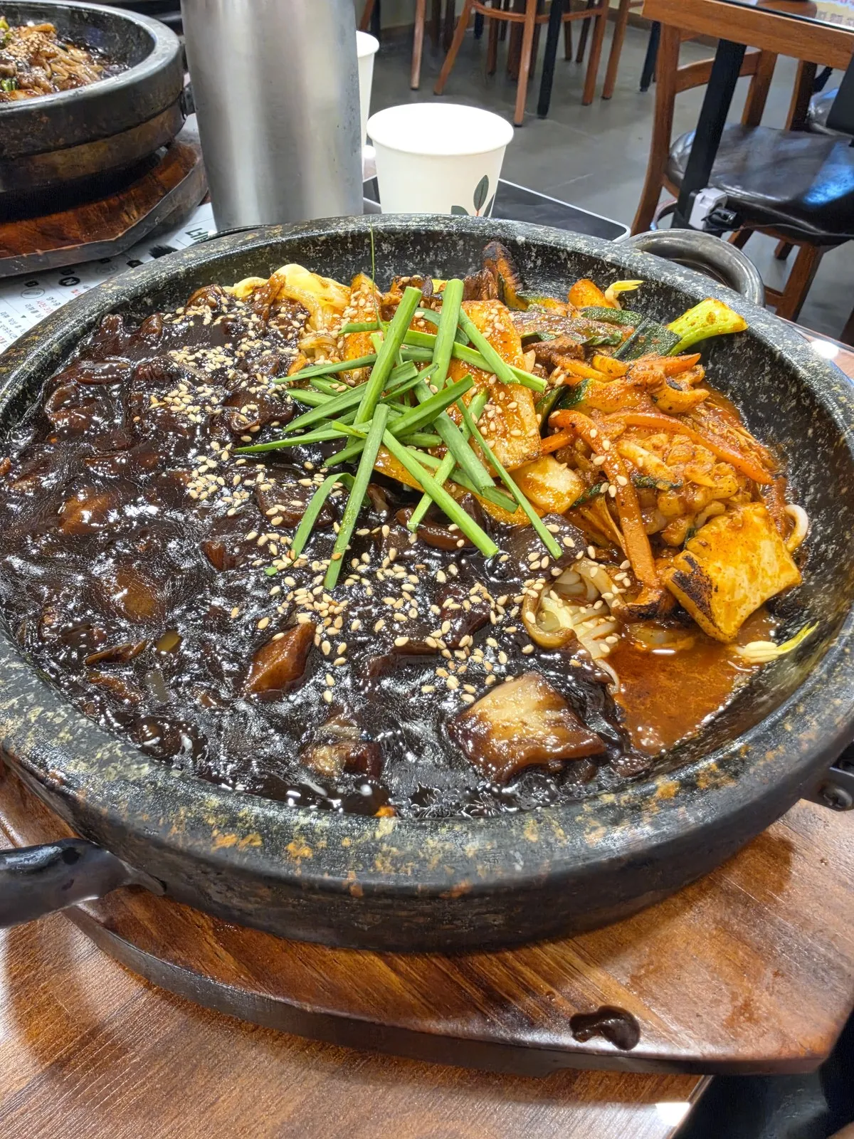 짜장과 매콤한 볶음면이 반반으로 담긴 돌판 — 가운데 실파로 경계를 나눴습니다
