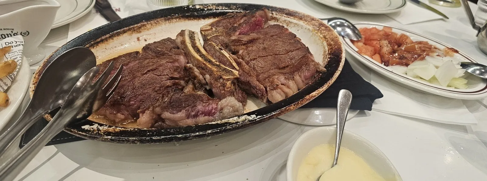 切り分けたステーキ — 横にはトマト・玉ねぎのサラダとマッシュポテト