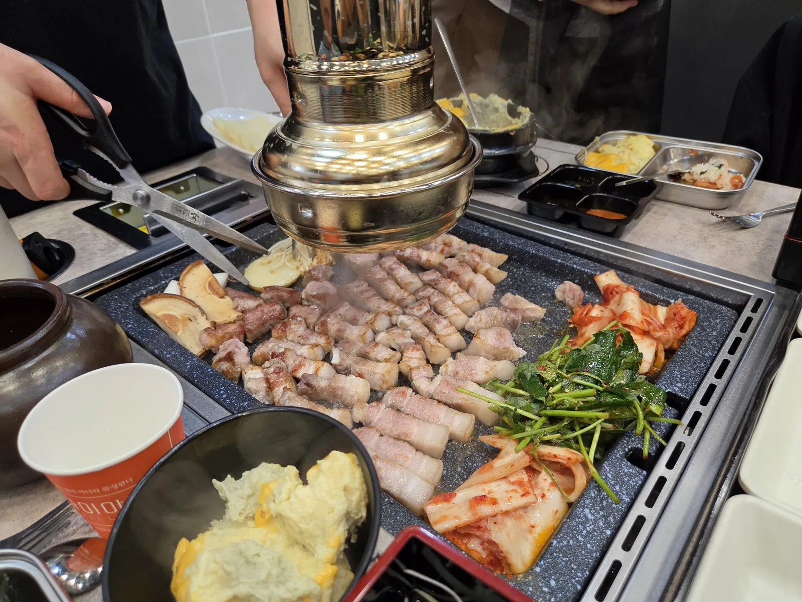 가위로 자르는 중 — 옆에서 김치와 나물 무침도 같이 구워요
