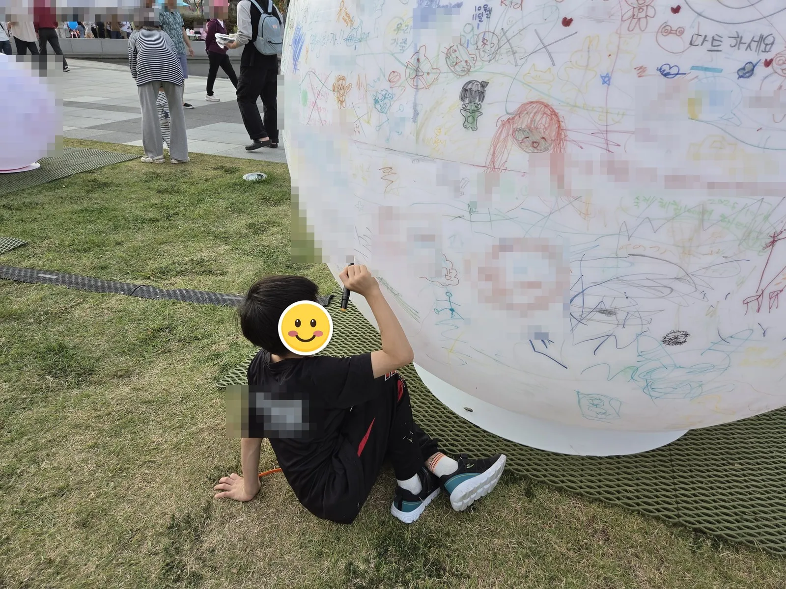 A huge white ball covered in visitors' doodles · the name and date on the ball are covered