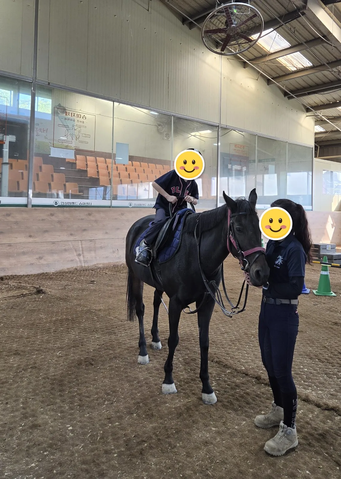 屋内乗馬場で馬に乗った子ども・顔はステッカーで隠しました