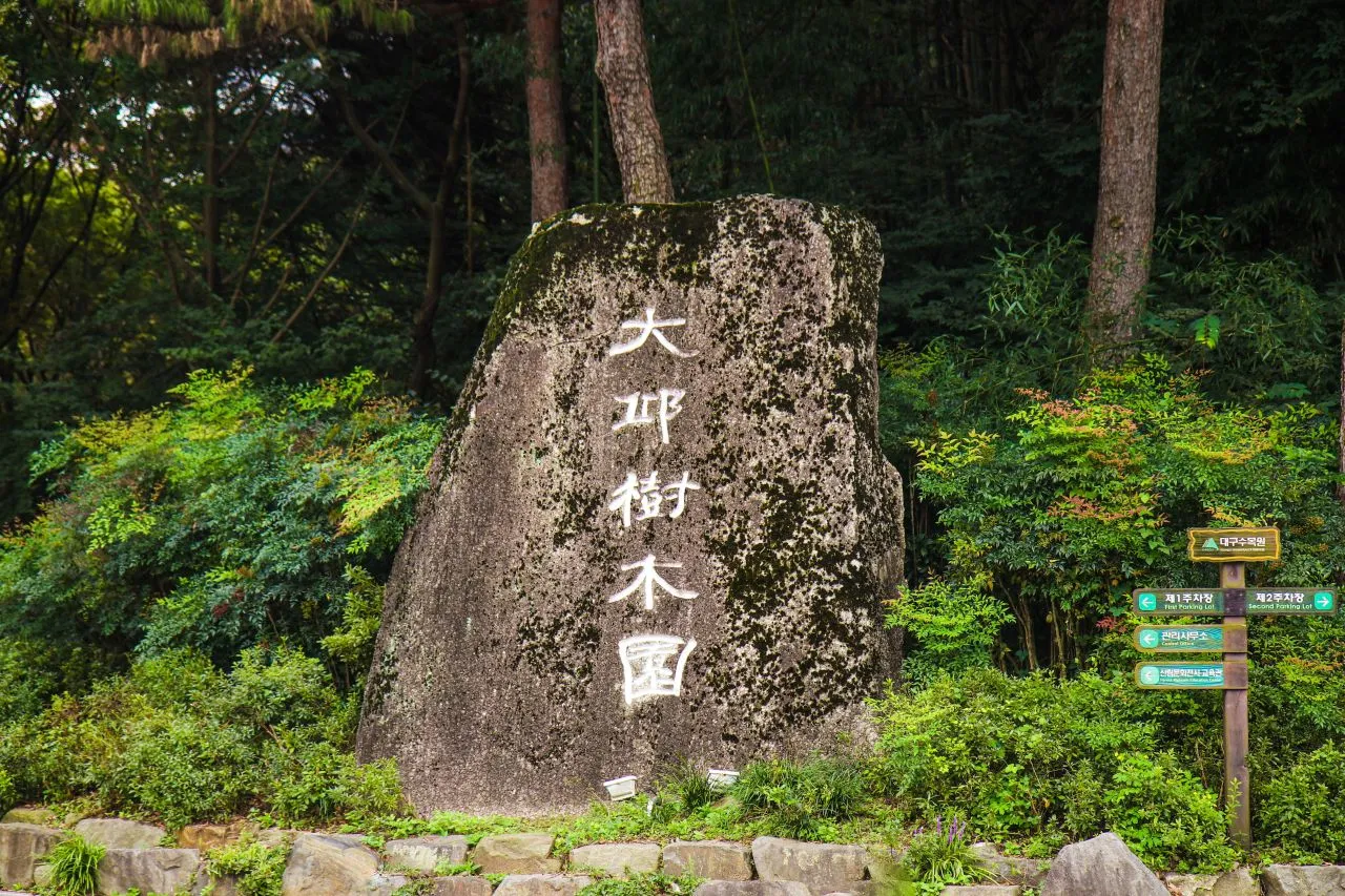 大邱樹木園 — 大邱樹木園標石與茂密樹木(2023年9月)(照片:韓國觀光公社觀光照片庫・攝影 김지영・公共授權第1類)