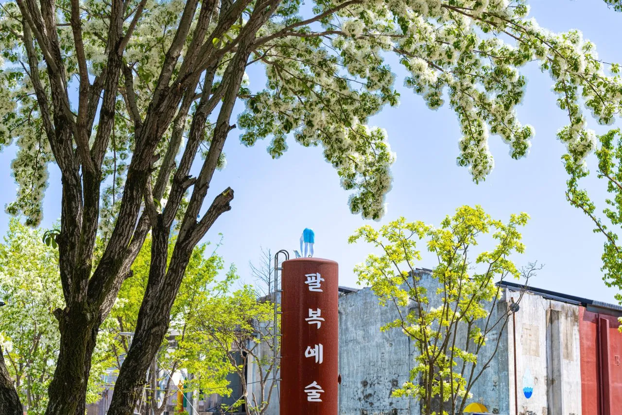 八福藝術工廠 — 李花樹下的八福藝術工廠標誌雕塑（2025年5月）（照片：韓國觀光公社觀光照片庫・攝影 조영권・公共授權第1類）
