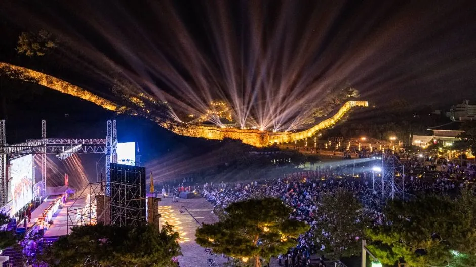 2025年慶典夜晚 — 燈光照耀的城牆下的舞台與觀眾