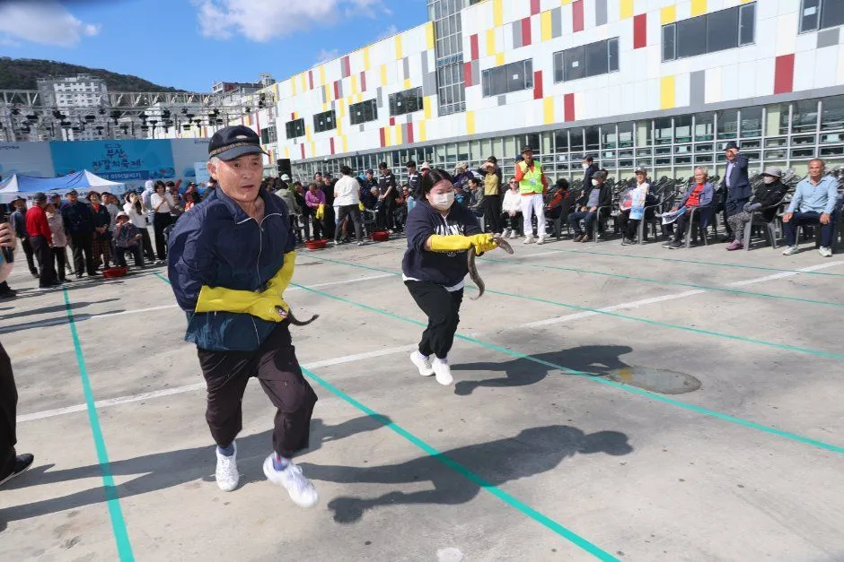 往屆慶典 — 戴黃色橡膠手套、手抓鰻魚奔跑的參加者（照片：韓國觀光公社・公共授權第3類）