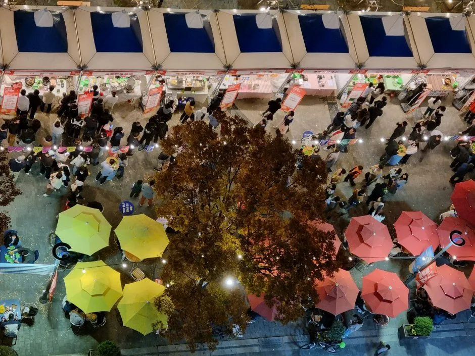 往屆活動夜晚 — 從上方俯瞰的用餐區，黃色與粉紅色陽傘下坐滿了人（照片：韓國觀光公社・公共授權第3類）