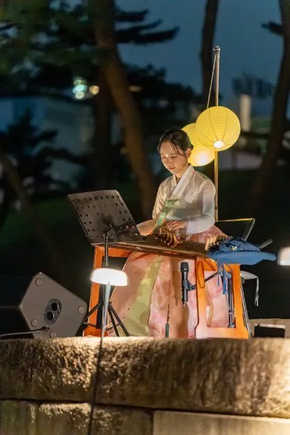 往屆慶典夜晚 — 燈籠下身穿韓服的樂手演奏傳統弦樂器