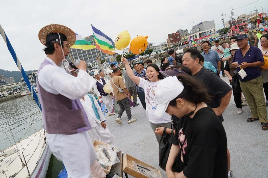 往屆慶典 — 在魚箱旁拿著麥克風的表演者與舉手的觀眾（照片：韓國觀光公社・公共授權第3類）
