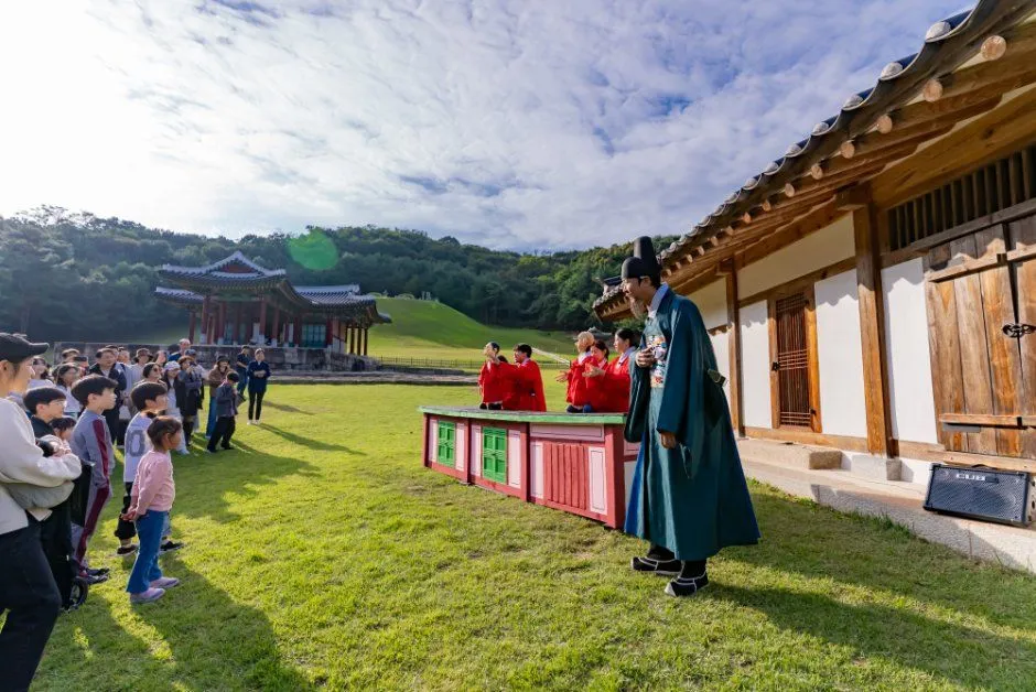 往屆慶典 — 草地上聚集在頭戴笠帽（갓）、身穿道袍的主持人面前的孩子與家人（照片：韓國觀光公社・公共授權第3類）