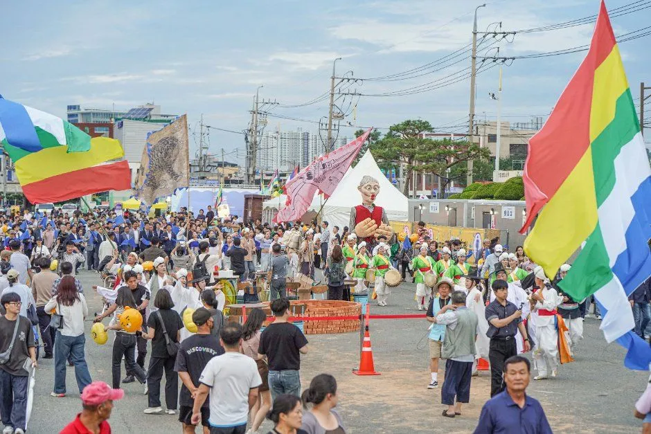 往屆慶典 — 以旗幟與巨型人偶開路的街頭遊行與圍觀人群